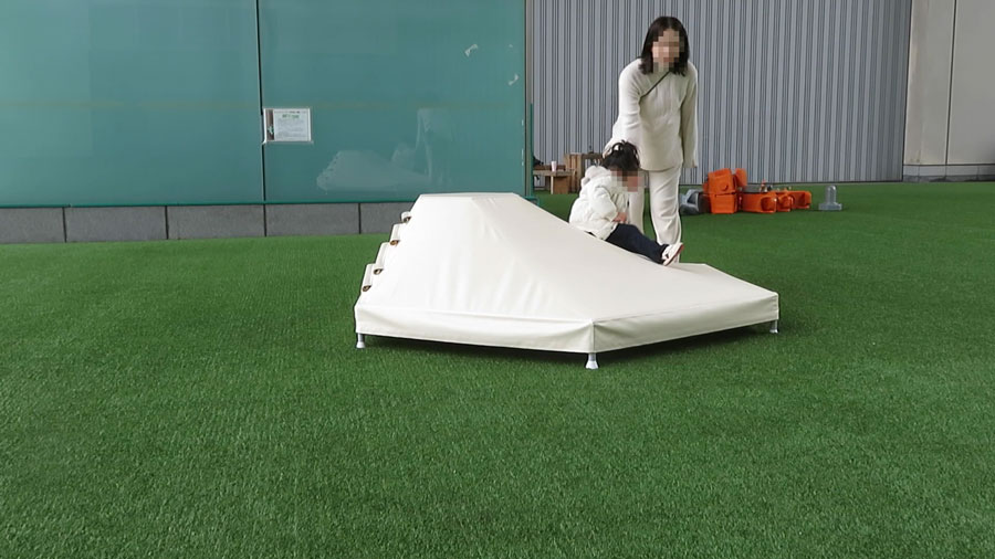 災害時の避難所を想定した大学との共同研究で開発中のテント膜製子ども用遊具を体験する幼児の様子①